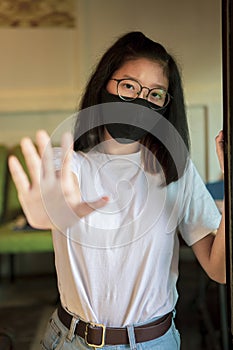 Asian teenager wearing protection mask and hand sign to not closer photo