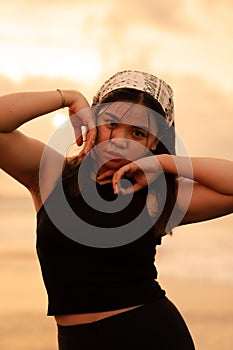 an Asian teenager wearing a white bandana and black shirt with a sexy expression on the beach sand