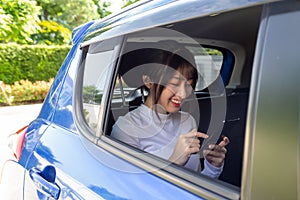 Asian teenager woman using a smartphone in back seat of car
