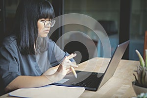 Asian teenager working on computer labtop at home living room