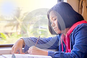 Asian teenager writing book or drawing picture on table