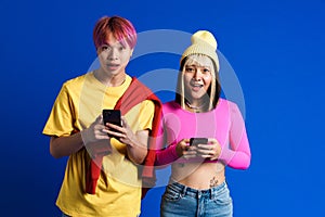 Asian teenagers expressing surprise while using cellphones