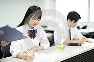 Asian teenagers in high school uniforms doing test in class