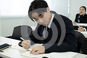 Asian teenagers in high school uniforms studying in class