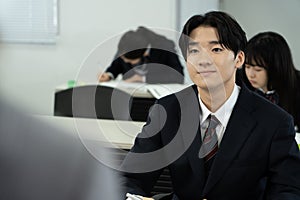 Asian teenagers in high school uniforms studying in class