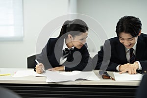 Asian teenagers in high school uniforms studying in class