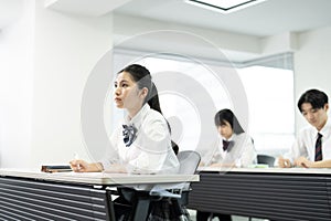 Asian teenagers in high school uniforms studying in class