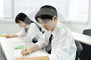 Asian teenagers in high school uniforms studying in class