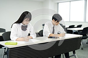 Asian teenagers in high school uniforms studying in class