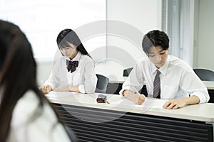 Asian teenagers in high school uniforms studying in class