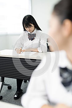 Asian teenagers in high school uniforms studying in class