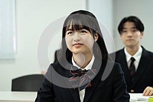 Asian teenagers in high school uniforms studying in class