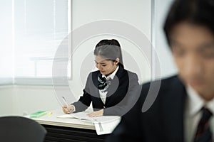 Asian teenagers in high school uniforms studying in class