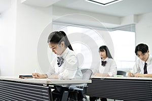 Asian teenagers in high school uniforms studying in class