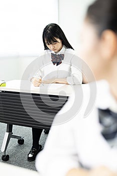 Asian teenagers in high school uniforms studying in class