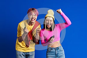 Asian teenagers with multicolored hair gesturing while using cellphones