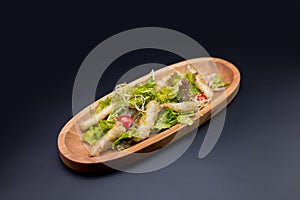 Asian Tempura chicken salad with lettuce and tomatoes served in wooden plate on dark background