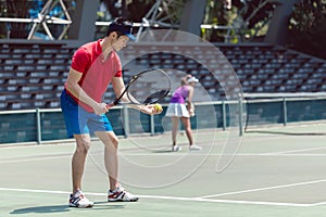 Asian tennis player ready to serve at the beginning of a doubles match