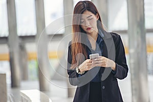 Asian Thai girl using mobile phone in business market.Person front view of Young Woman holding smartphone via internet to sending