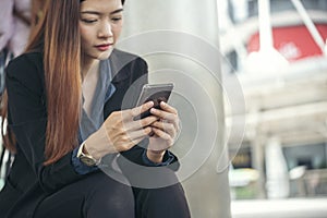 Asian Thai girl using mobile phone in business market.Person front view of Young Woman holding smartphone via internet to sending