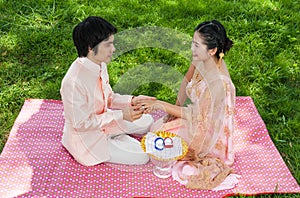 Asian Thai groom is wearing wedding ring to his bride in Thai ceremony