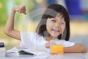 Asian Thai kid girl A cute face with a bright smile, wearing a white shirt, in good health. sitting outdoors There are books on