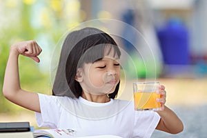 Asian Thai kid girl A cute face with a bright smile, wearing a white shirt, in good health. sitting outdoors There are books on