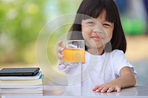 Asian Thai kid girl A cute face with a bright smile, wearing a white shirt, in good health. sitting outdoors There are books on