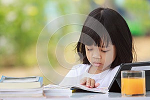 Asian Thai kid girl A cute face with a bright smile, wearing a white shirt, in good health. sitting outdoors There are books on