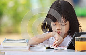 Asian Thai kid girl A cute face with a bright smile, wearing a white shirt, in good health. sitting outdoors There are books on