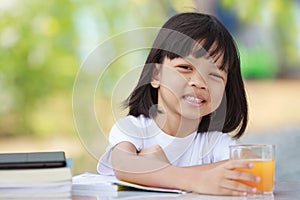 Asian Thai kid girl A cute face with a bright smile, wearing a white shirt, in good health. sitting outdoors There are books on