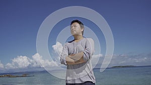 Asian Thai man stands on the beach, Camera move around him.