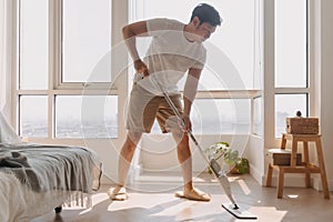 Asian Thai man using mop for cleaning floor in living room apartment, Man do household chores, housework concept.