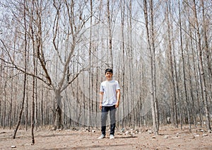 Asian Thai man in white casual stands alone in dry pie forest