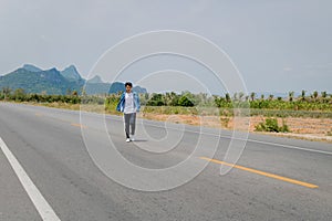 Asian Thai man in white casual stands alone on the empty road