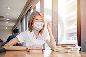 Asian Thai university girl teen waring face mask for healthy prevent covid in library photo