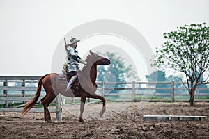 Asian Thai Warrior in traditional armor suit riding horse in rural farm background. Vintage Retro war costume concept