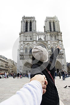 Asian thai woman lead someone by the hand and hold at Cathedrale Notre-Dame de Paris