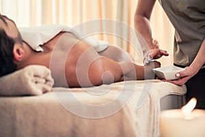 Asian therapist applying manually rejuvenating lotion at luxury