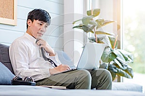 Asian thoughtful young handsome professional successful male businessman employee in formal business outfit sitting on cozy sofa