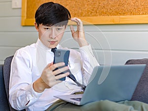 Asian thoughtful young handsome professional successful male businessman employee in formal business outfit sitting on cozy sofa