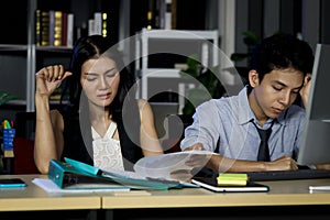 Asian tired staff officer business man and woman work hard overtime together at night in office, night shift worker have overwork