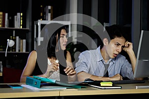 Asian tired staff officer business man and woman work hard overtime together at night in office, night shift worker have overwork