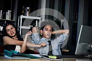 Asian tired staff officers try to relieve physical tension after work hard overtime at night in office, having overwork project