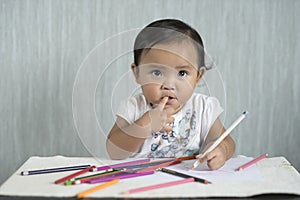 Asian toddler / baby girl is having fun learning to use pencils.