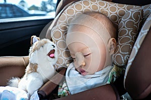 Asian toddler boy child sleeping in car seat. Child traveling safety on the road. Safe way to travel fastened seat belts in