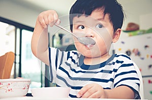 Asian toddler boy eating on high chair