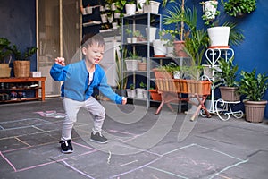 Asian toddler boy having fun jumping, playing hopscotch at home