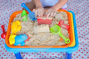 Asian toddler boy playing with kinetic sand at home