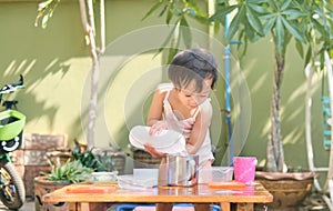 Asian toddler girl having fun pouring water into cup, Wet Pouring Montessori Preschool Practical Life Activities, Fine Motor photo